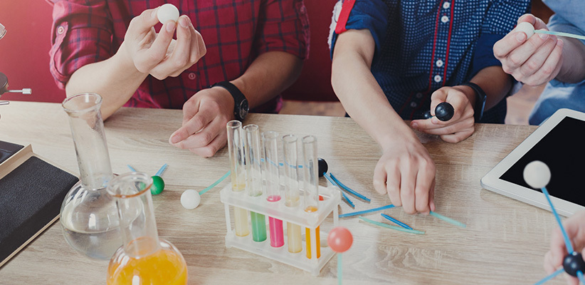 Teens assemble DNA model on a workbench.